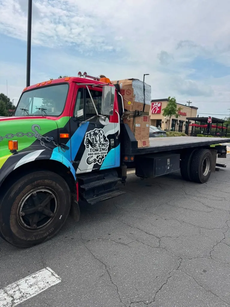 Nelms Towing LLC flatbed transporting commercial cargo crates and industrial machinery