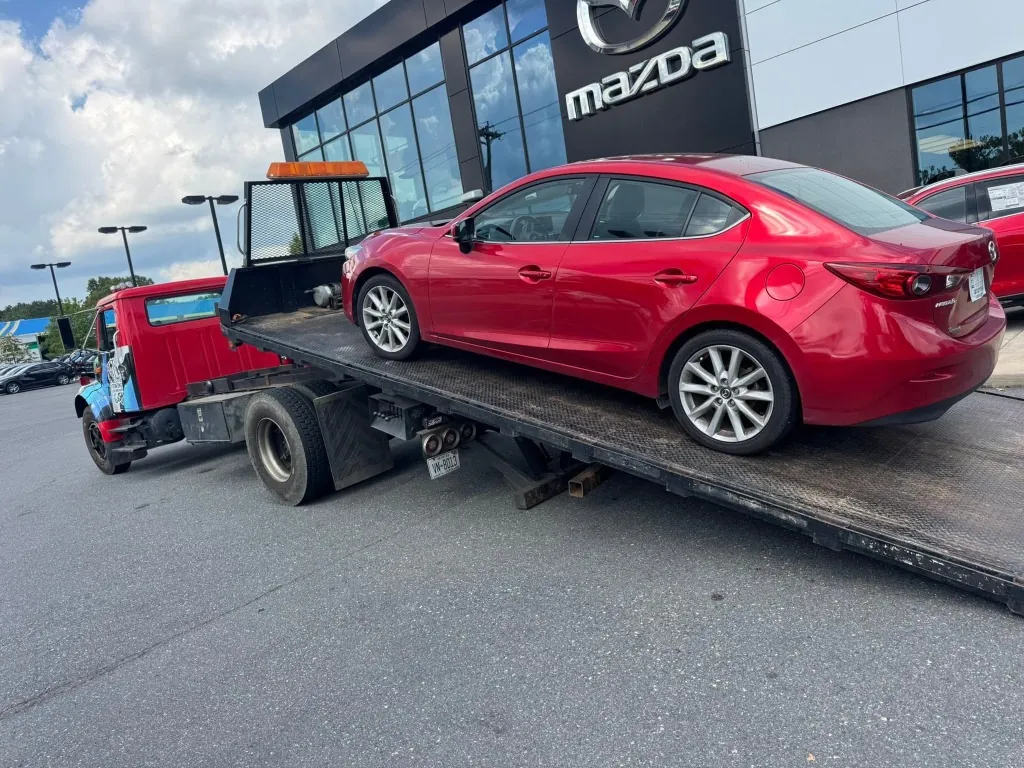 Nelms Towing LLC flatbed loading red Mazda sedan at Mazda dealership in Charlotte NC
