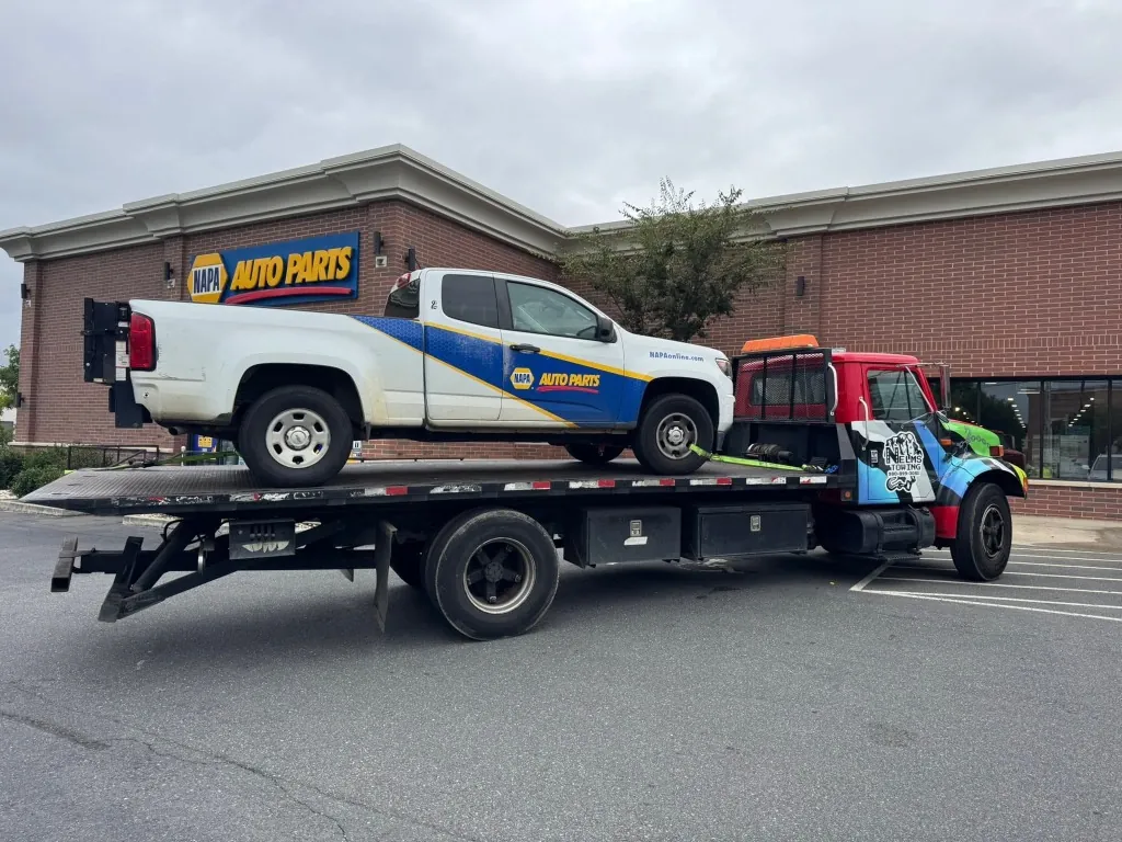 Nelms Towing LLC flatbed towing NAPA Auto Parts commercial delivery truck outside NAPA store