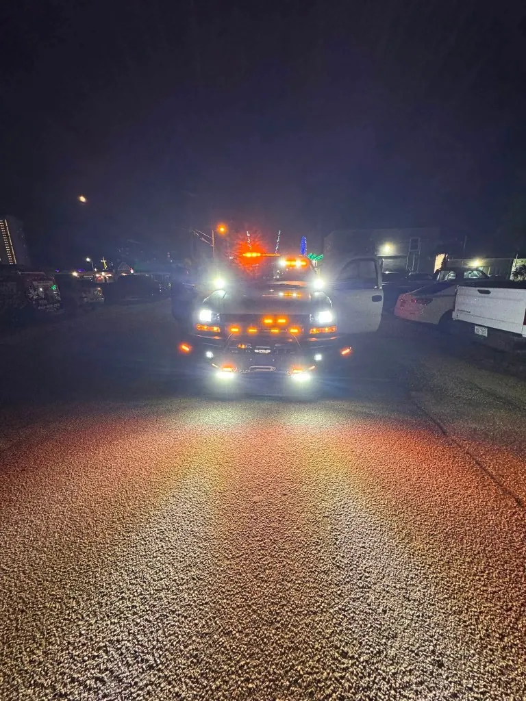Nelms Towing LLC emergency tow truck with LED warning strobes lit at night