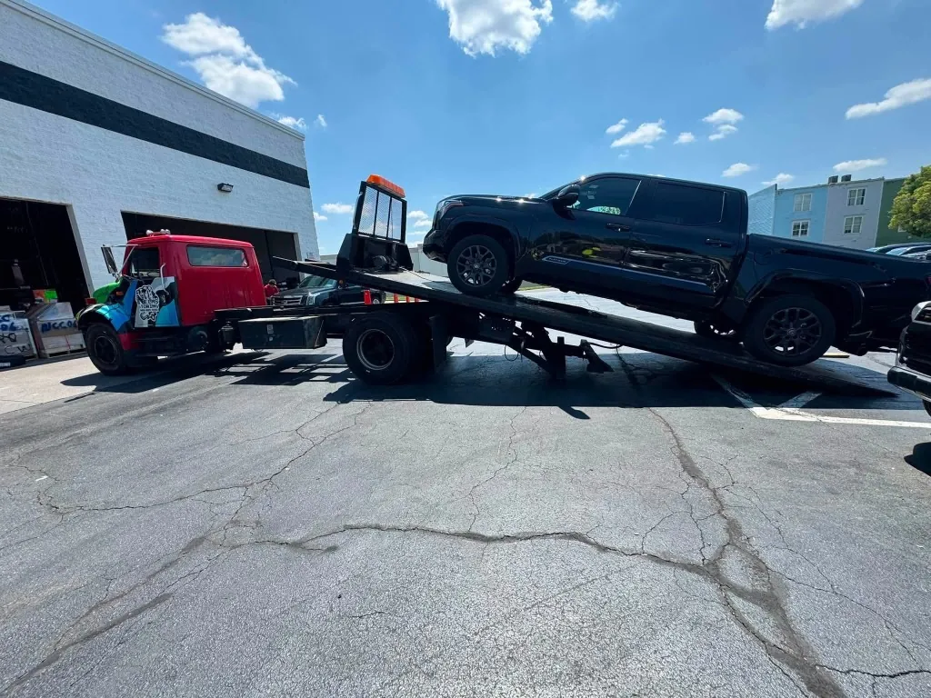 Nelms Towing LLC wrecker winching a heavy work pickup truck onto rollback flatbed